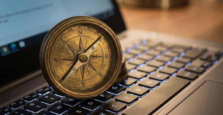 Uma bússola antiga sobre um teclado de computador, representando a direção e os conselhos de vida na transição de carreira.