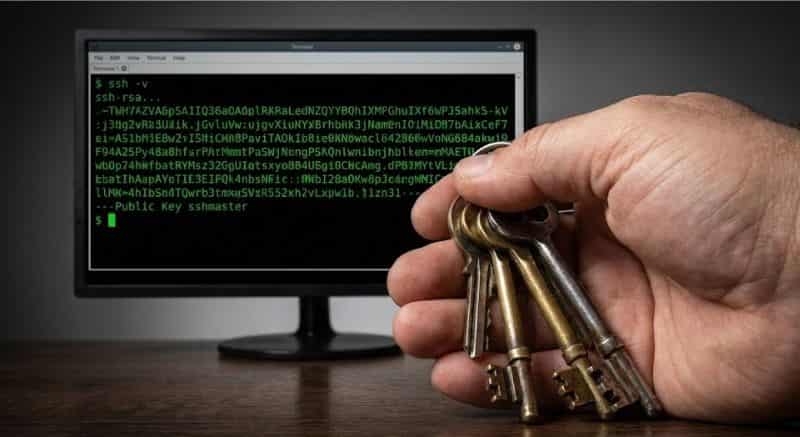 Segurança em Servidores Linux:Close-up de mão segurando chaves físicas de metal ao lado de um monitor exibindo uma chave de criptografia SSH.